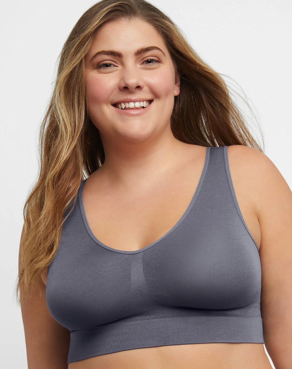 Just My Size plus-size model wearing a blush pink wireless satin bra, showcasing confident, comfortable style